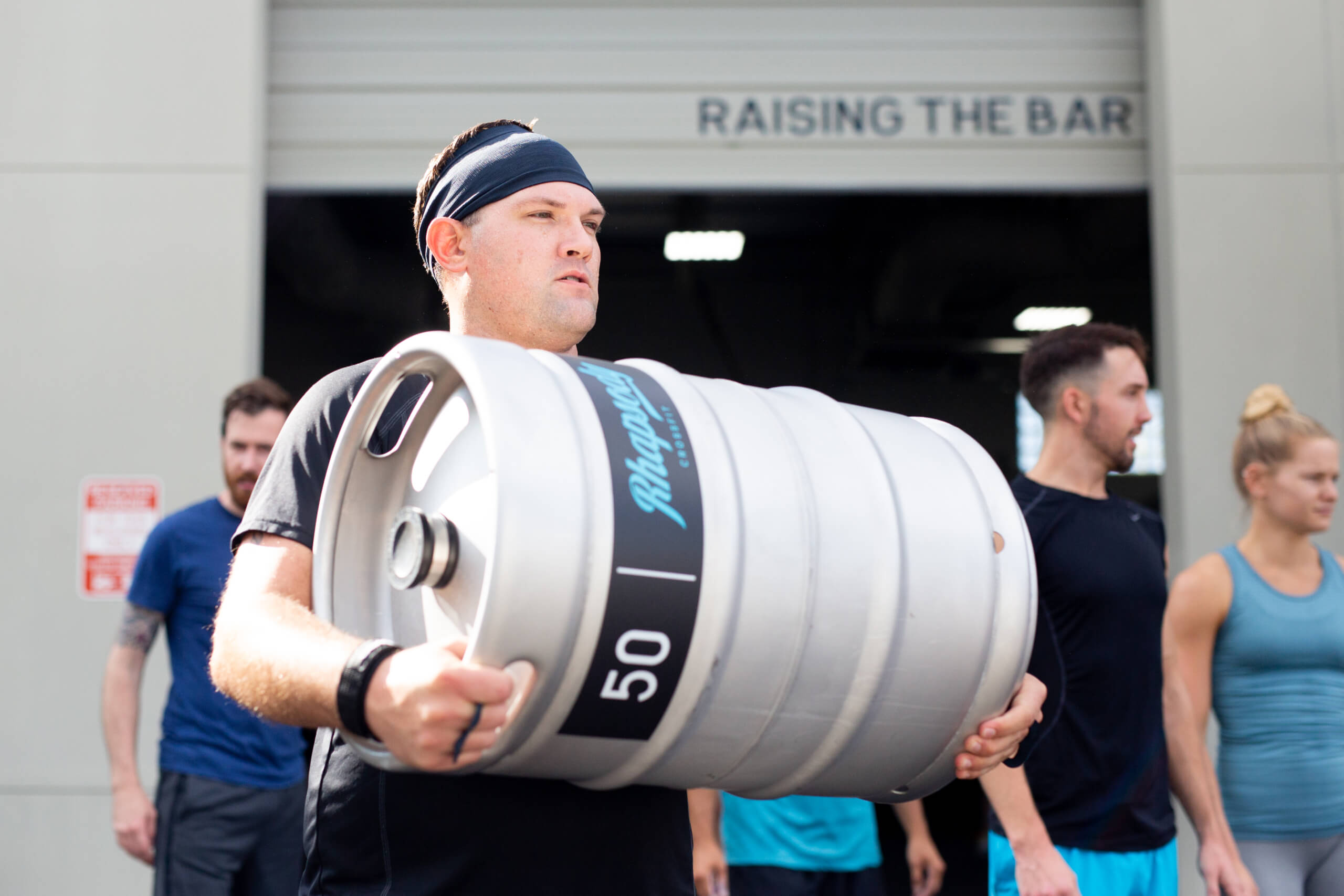 A man carrying a keg of beer in front of other people.
